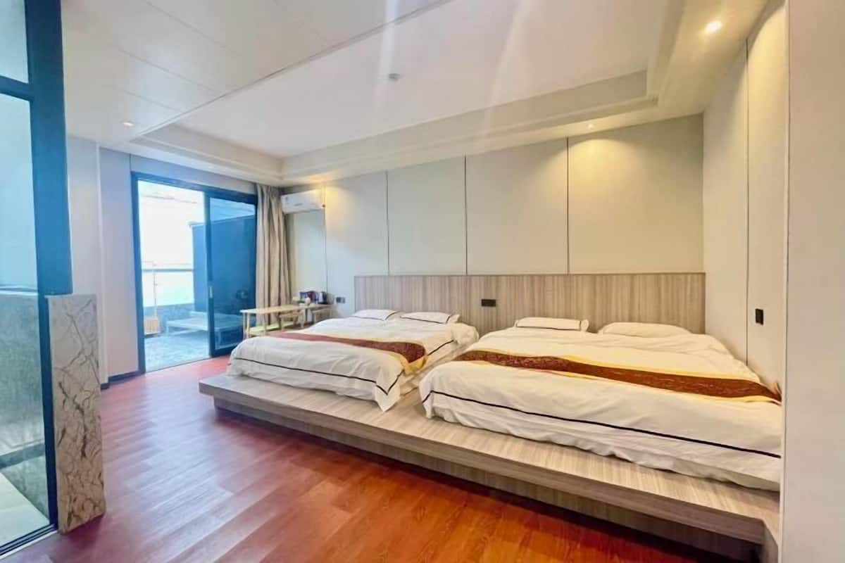 A modern hotel room with two beds, a marble column, and a glass door leading to a balcony.