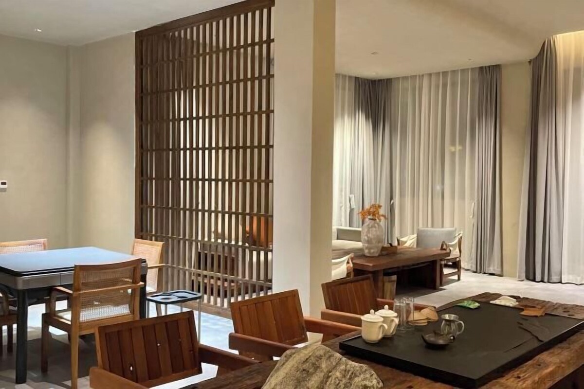 A modern room with a dining area, a sofa set, and a large window with curtains.