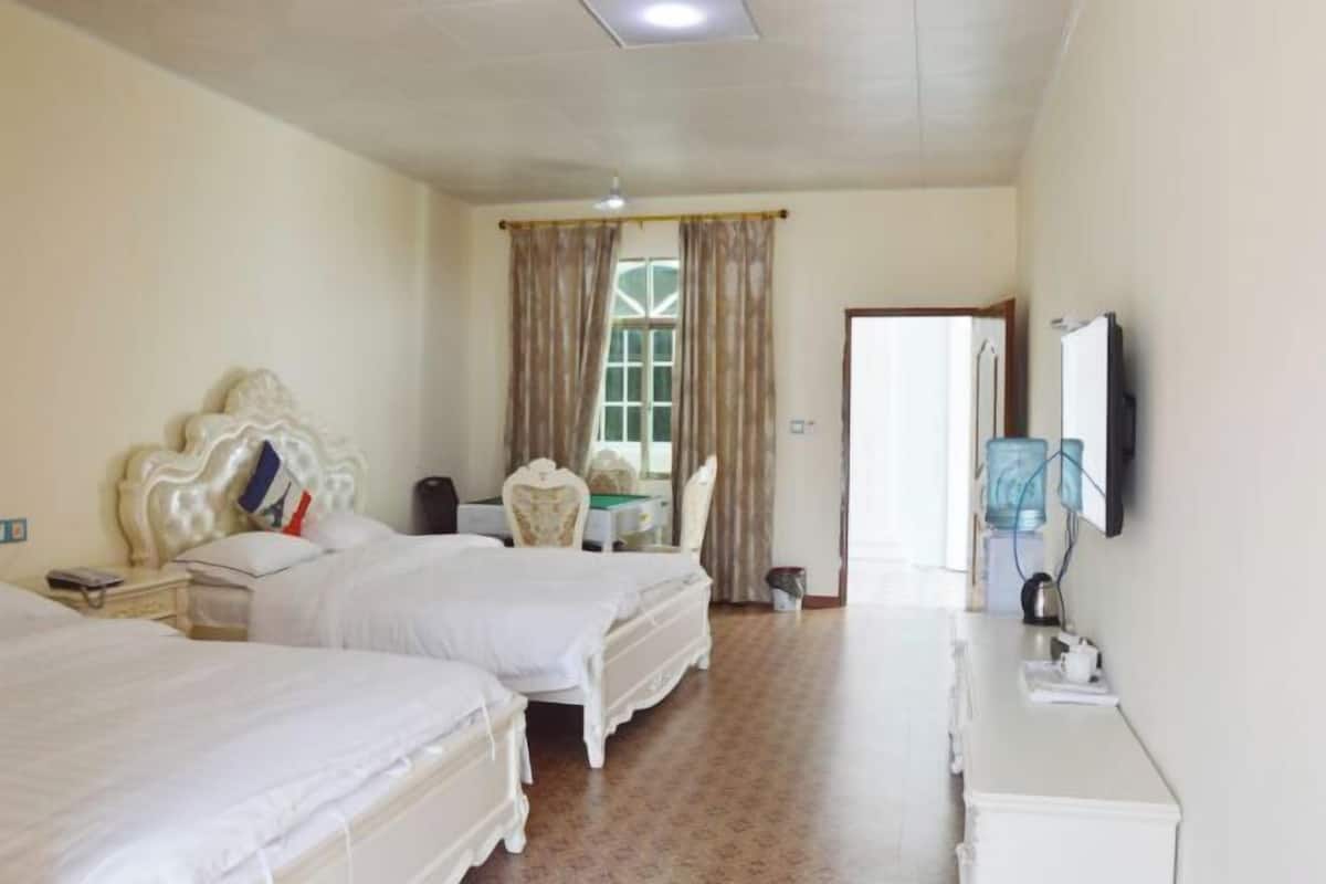 A hotel room with two beds, a desk, a chair, a television, and a water dispenser.