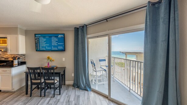 A balcony with a view of the sea, a dining area with chairs and a table, and a menu board on the wall. - Condo On The Beach - Ocean Side View Balcony (Belleair Beach)