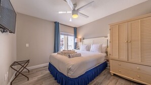A bedroom with a bed, a ceiling fan, a wardrobe, and a window with curtains. - Condo On The Beach - Ocean Side View Balcony (Belleair Beach)