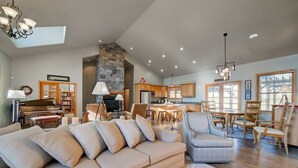 Amplia sala de estar con un sofá beige grande, un piano y una chimenea de piedra.