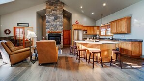 Una cocina amplia con armarios de madera, una chimenea de piedra y una isla grande con taburetes de bar.