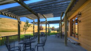 Un patio techado con mobiliario exterior y vistas a una colina.