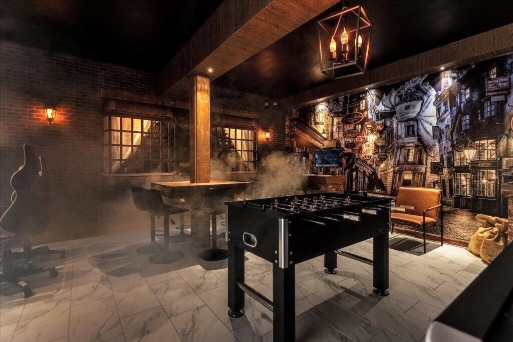 A room with a foosball table, a bar area, and a mural of a cityscape.