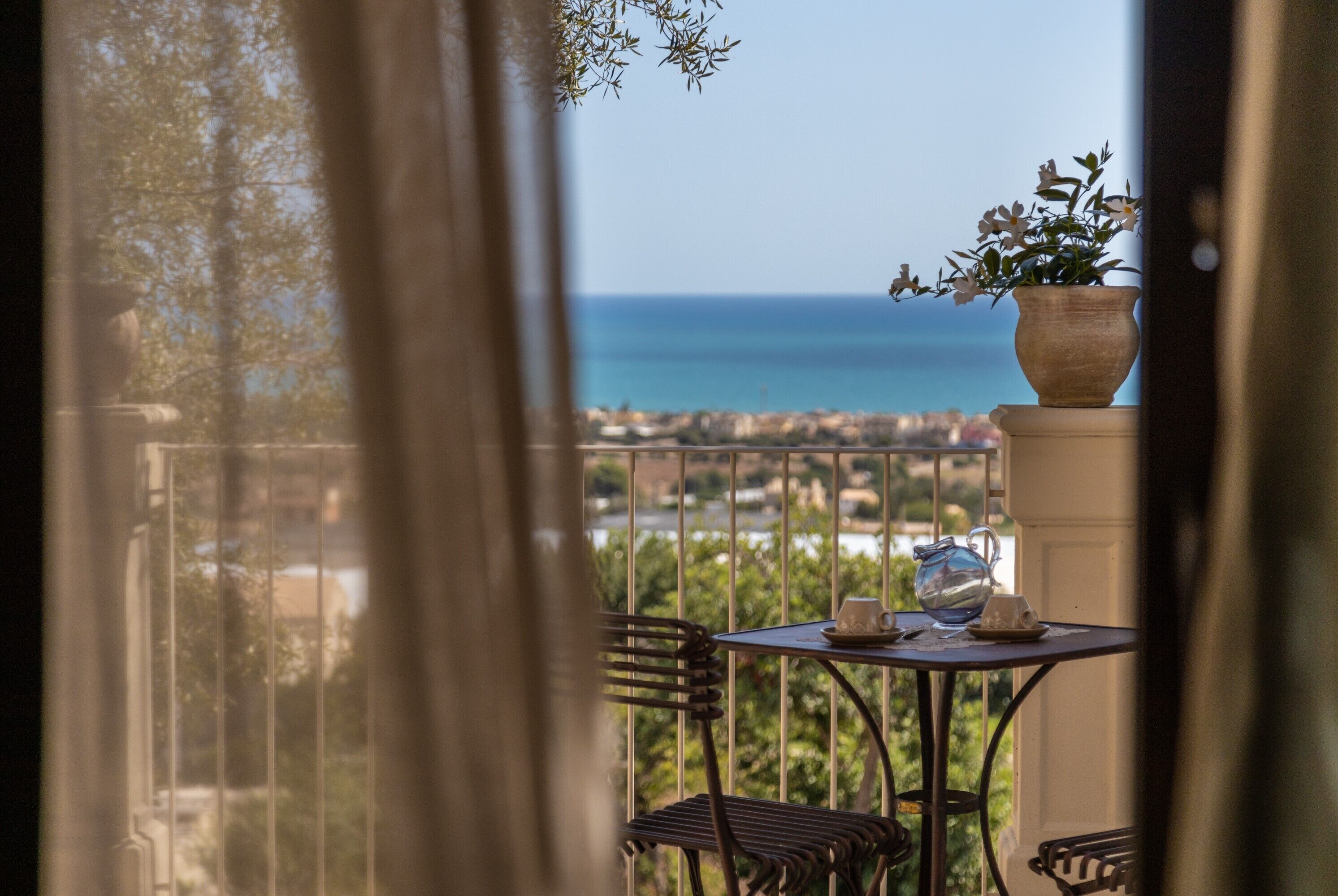 A balcony with a table, chairs, and a potted plant.