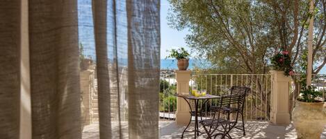 Un patio exterior con una mesa y sillas, una planta en maceta y vista al mar.