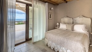 A bedroom with a large bed, a view through a sliding glass door, and a rustic ceiling. - RoccaSeta dimore siciliane (Scicli)