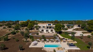 A villa with a swimming pool, outdoor seating, and a view of the surrounding landscape. - RoccaSeta dimore siciliane (Scicli)