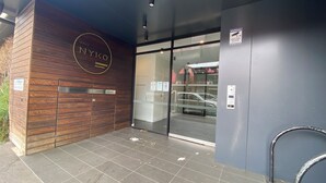 A building entrance with a wooden facade, a glass door, and a metal railing. - Modern 1BR Apt in Brunswick East, 15 mins from CBD (Brunswick East)
