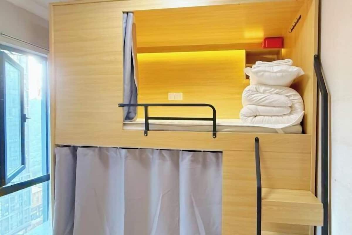 Ein Etagenbett mit ausklappbarem Schreibtisch und einem Fenster mit Vorhängen.