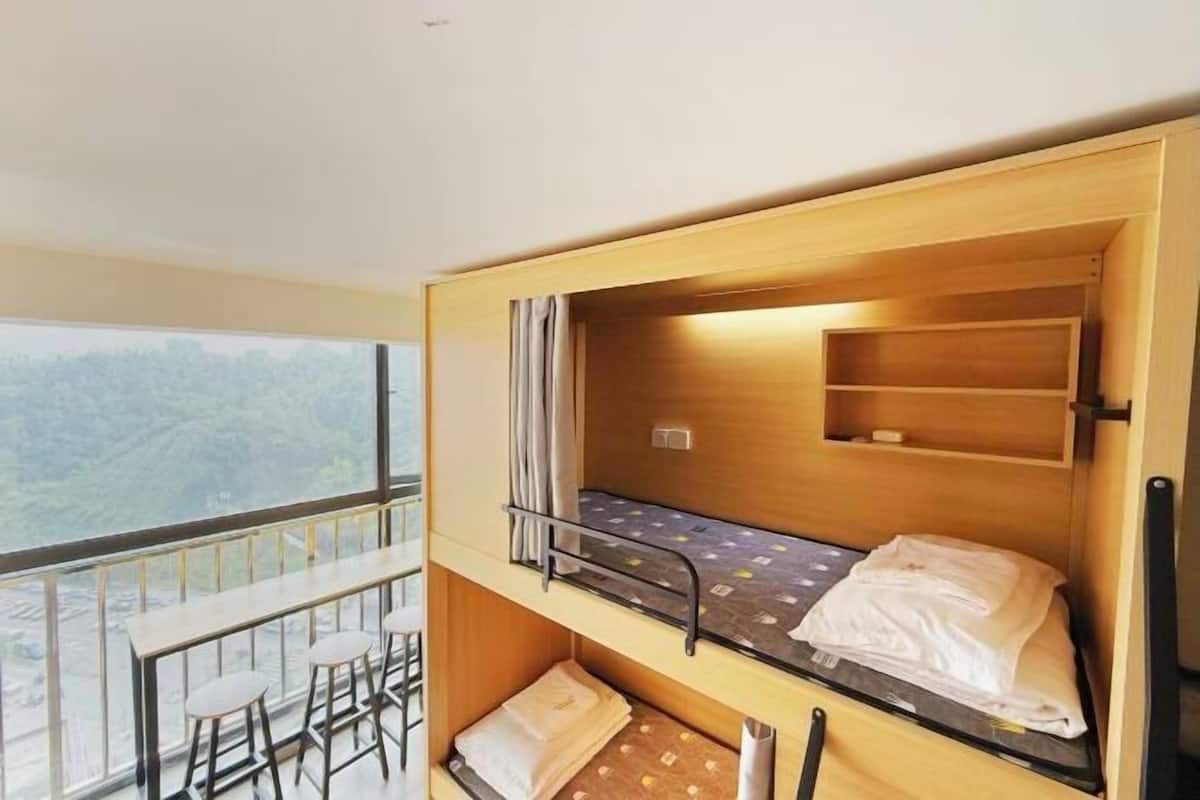 Ein Schlafraum mit Etagenbetten, einem Balkon, einem kleinen Tisch und Stühlen.