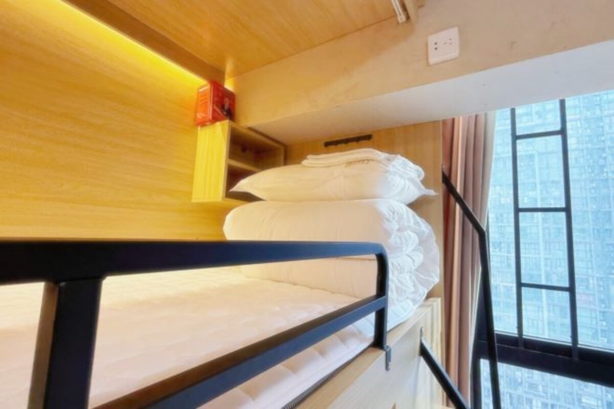Una cama litera con cabecera de madera y una ventana con vista a la ciudad.