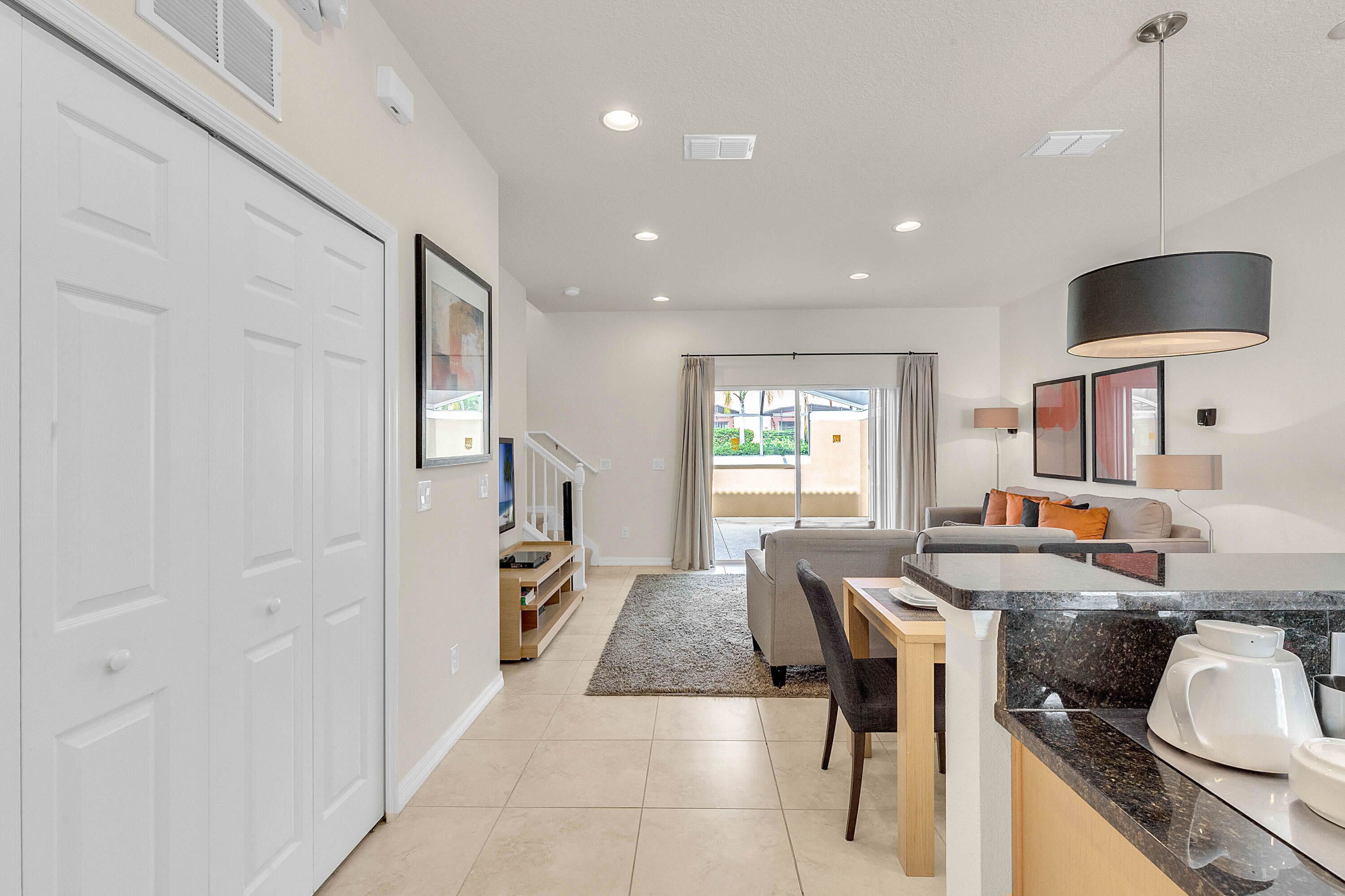 A modern kitchen with a dining area, a large window, and a sliding door leading to a balcony.