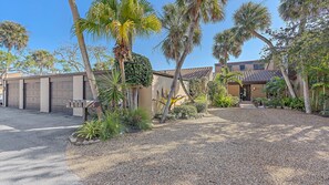 A residential property with a garage, a front yard with gravel, and palm trees.
