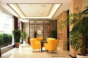 Un vestíbulo de hotel con una zona de estar, un ventanal grande y una pared decorativa.