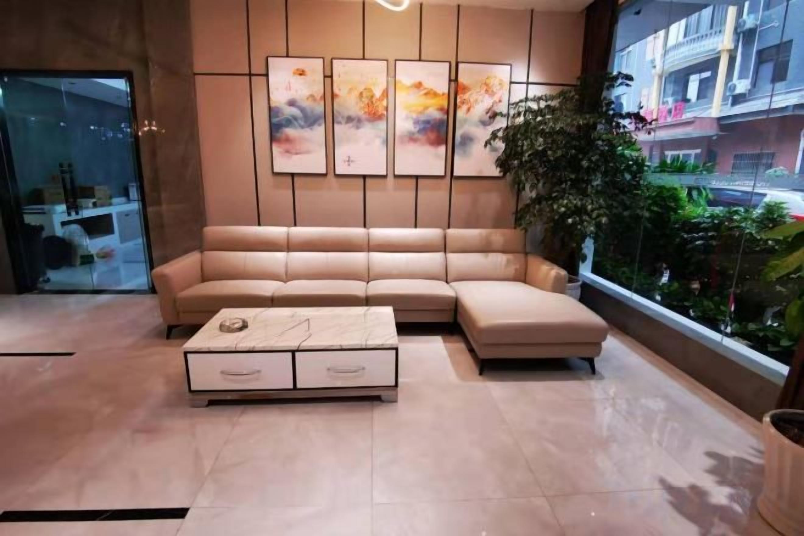 Una sala moderna con un sofá seccional color beige, una mesa de centro blanca con cajones y arte abstracto en la pared.