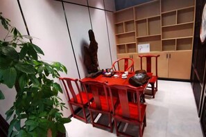 A dining area with a table and chairs, a potted plant, and a shelf unit with storage compartments. - Homeinn Ease Hotel (Enshi Railway Station) (Enshi City)