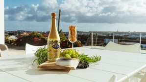 Een tafel met een fles Blue Nun 24K Gold Edition champagne, een stukje brood en een schaal druiven op een witte tafelkleed.