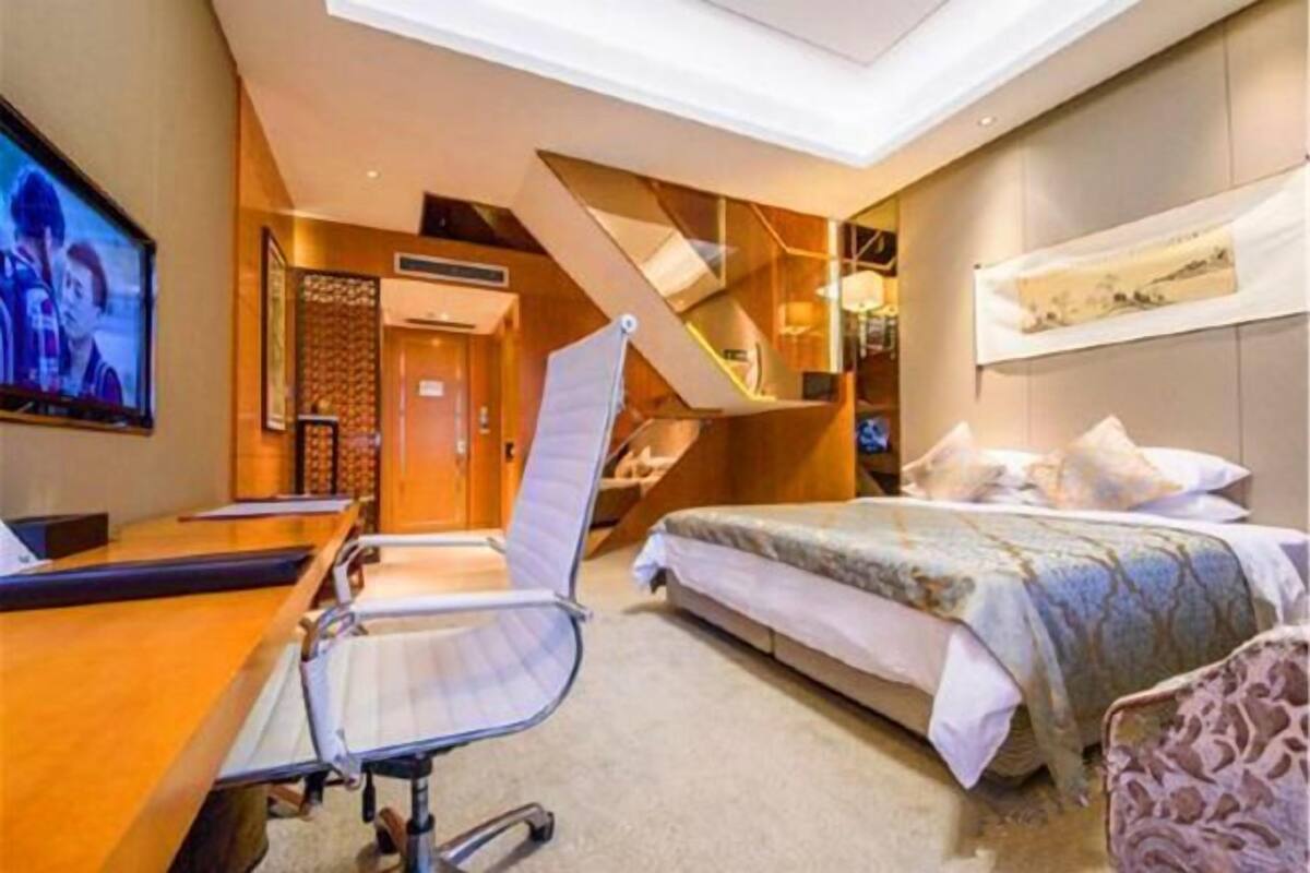 Hotelkamer met een bed, bureau, stoel, televisie en een trap.
