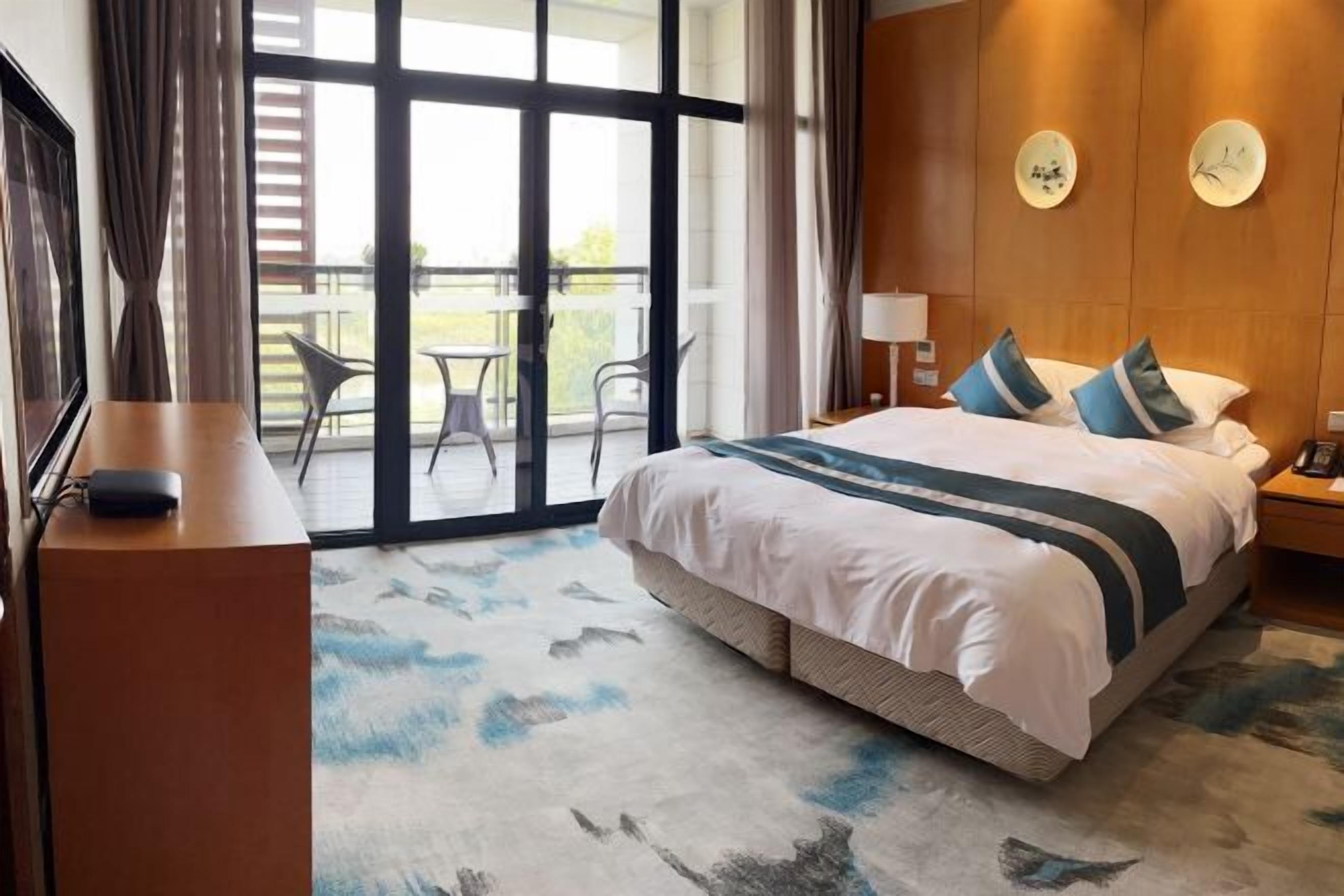 Une chambre d’hôtel avec un grand lit, un bureau, une chaise et une vue sur l’extérieur.