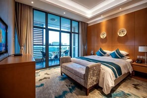 A hotel room with a large bed, a sofa, a TV, and a balcony with a view.