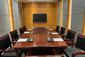 Una sala conferenze con un lungo tavolo, sedie e uno schermo.