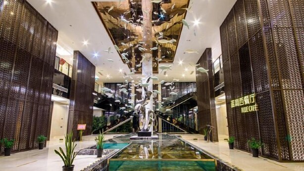 A spacious lobby with a central water feature, a staircase, and modern decor.