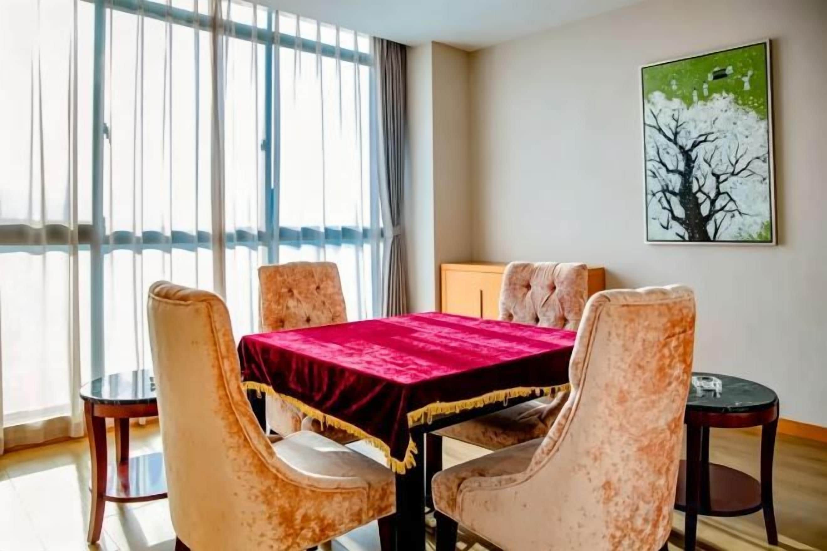 Een eetruimte met een tafel en stoelen, een raam met gordijnen en een schilderij aan de muur.