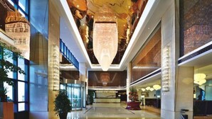A spacious lobby with a high ceiling, large chandeliers, and a reception desk.