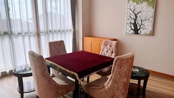 A dining area with a table and four chairs, a cabinet, and a painting on the wall.