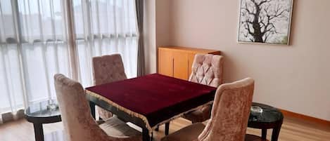 Un comedor con una mesa y cuatro sillas, un armario y un cuadro en la pared.