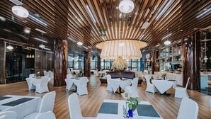 A modern interior with a wooden ceiling, round tables, and white chairs.