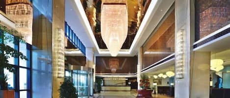 A spacious lobby with a high ceiling, large chandeliers, and a modern design.