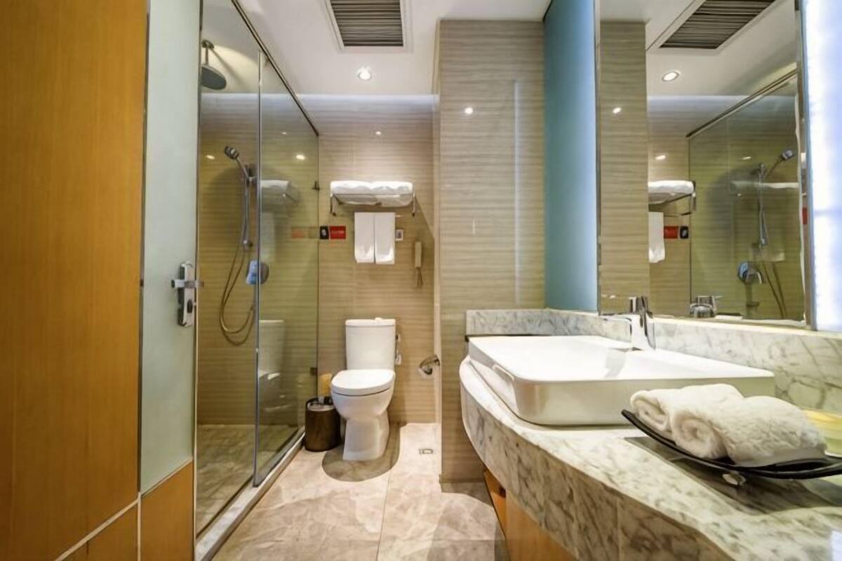 A modern bathroom with a glass shower enclosure, a large sink, and a marble countertop.