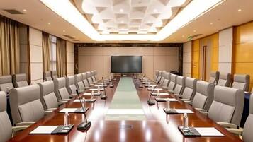 Una sala de conferencias con una larga mesa, varias sillas, una pantalla de proyector y un ventanal grande.