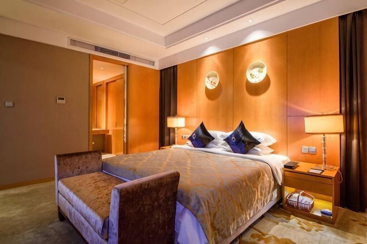 Een hotelkamer met een groot bed, twee nachtkastjes, een stoel en een spiegel.
