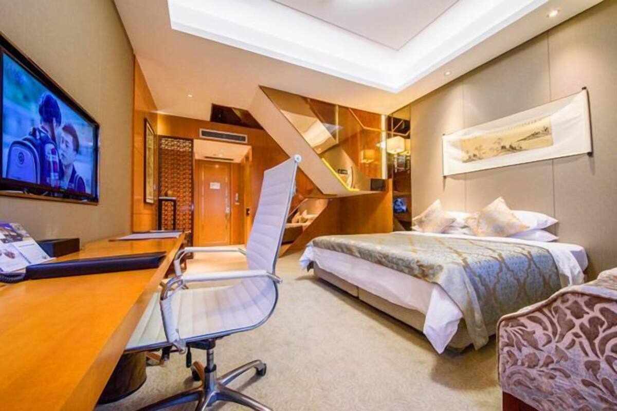 Een hotelkamer met een bureau, een bed, een stoel, een televisie en een trap.