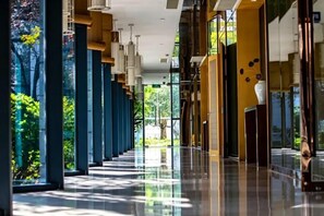 A long corridor with a reflective floor, large windows, and a view of greenery outside. - Scholars Hotel (Tongzhou Bay Business Center Yacht Club) (Nantong)