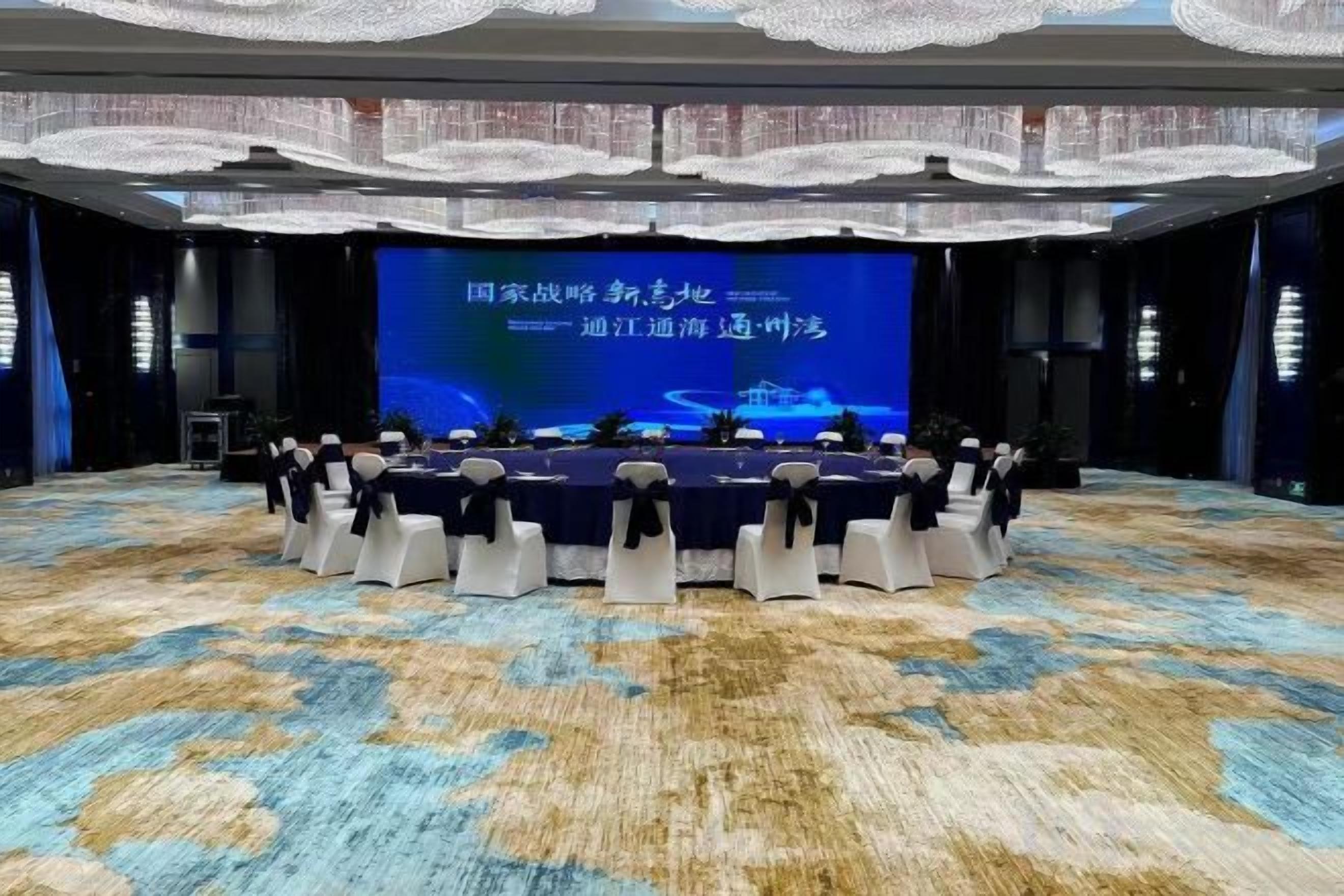 A conference room with a stage, rows of chairs, and a carpeted floor.
