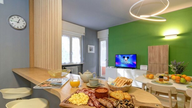 A breakfast setup with eggs, bacon, sausages, mushrooms, toast, and orange juice on a wooden board.