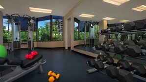 A gym with exercise equipment, large windows, and a view of greenery.