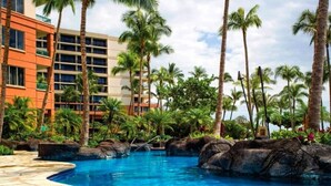A resort pool with palm trees and a building in the background.
