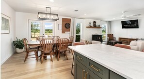 A modern kitchen with a large island, wooden chairs, and a dining table. - 4/2 Ranch | Hot Tub | Full Kitchen | Family Friendly (Fredericksburg)