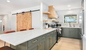 A modern kitchen with a large island, built-in appliances, and a view to the outdoors. - 4/2 Ranch | Hot Tub | Full Kitchen | Family Friendly (Fredericksburg)