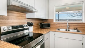 Una cocina moderna con electrodomésticos de acero inoxidable, encimeras de madera y un ventanal con vistas.