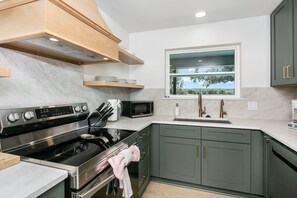 A modern kitchen with a built-in stove, microwave, and stainless steel sink. - 4/2 Ranch | Hot Tub | Full Kitchen | Family Friendly (Fredericksburg)