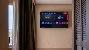 Una stanza con una televisione a muro che mostra diversi servizi di streaming.