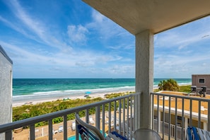 A balcony with a view of the beach and ocean.