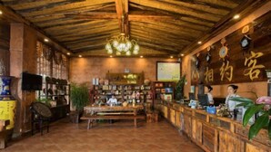 Un interior rústico con un mostrador de recepción de madera, una araña y una pared con relojes y un letrero.